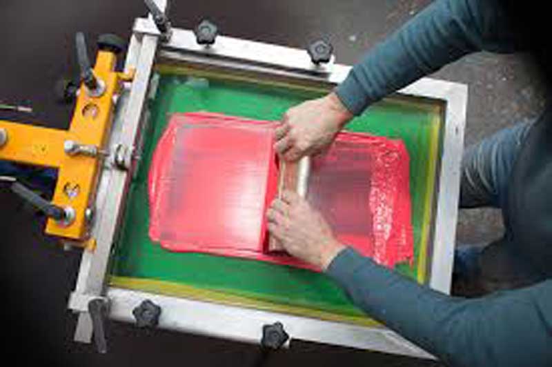 A screen printing machine applying a logo onto a silicone product
